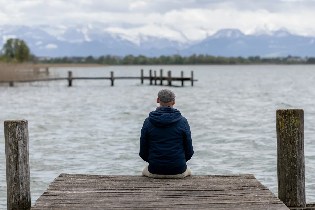 Die sexuelle Orientierung eines Pfäffiker Primarlehrers kam bei einem Teil der Eltern nicht gut an. Nach dem Sexualkundeunterricht kam es zum Eklat. Mann sieht einen Mann von hinten, der auf einem Steg an einem See sitzt.